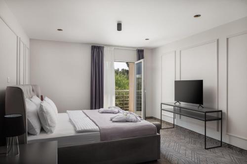 波尔Zlatni Rat Beach Resort的一间白色卧室,配有床和电视