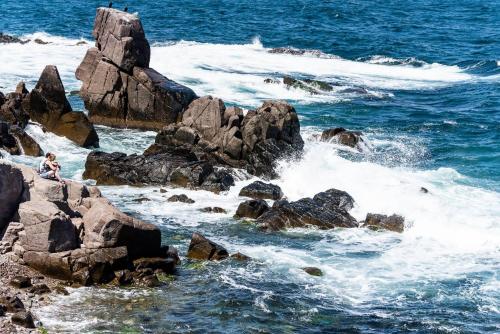 杜尼Hotel Gamartata的坐在海洋中一些岩石上的人