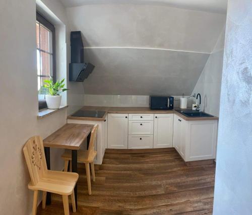 斯罗姆韦斯尼Pokoje u Basi的厨房配有白色橱柜和木桌