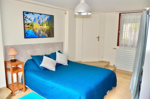 塞纳河畔伊夫里Le Jardin Paris的白色卧室内的一张蓝色床和蓝色毯子