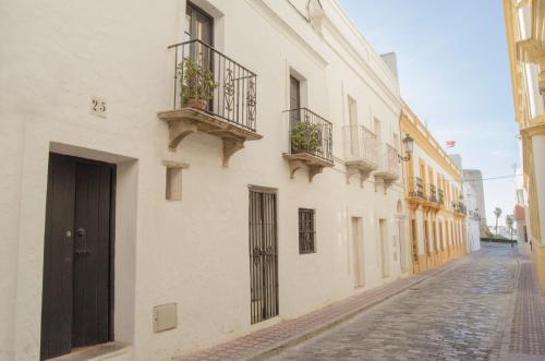 塔里法Apartamentos Tarifa Castillo的一条空的街道,有白色的建筑和盆栽植物