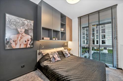 罗兹Luxury Copper Apartment的一间卧室设有一张大床和一个大窗户