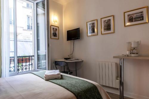 巴黎Montmartre Apartments Chagall的一间卧室设有一张床、一台电视和一个窗口。