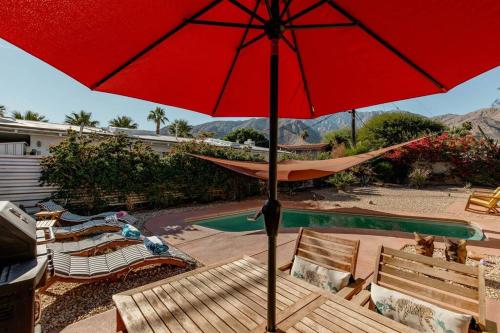 棕榈泉The Yorba Oasis w/Pool的一个带椅子和吊床的庭院里的红伞