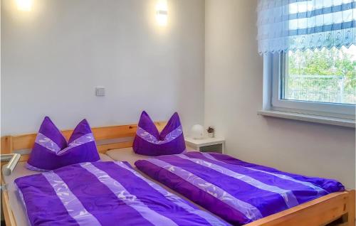 BehrenhoffNice Home In Behrenhoff With Kitchen的卧室配有紫色枕头,床边设有窗户