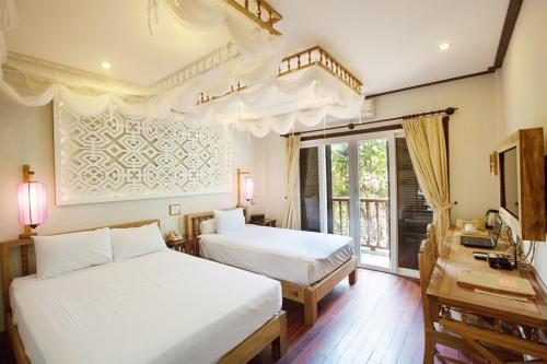 会安Hoi An Pho Library Hotel的一间卧室设有两张床、一张桌子和一个窗口。