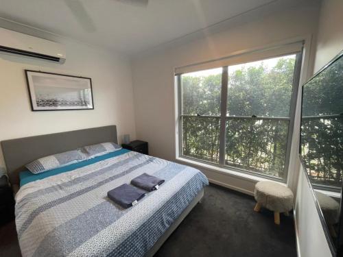 StrathpineTropical Ocean Vibe Holiday House in Strathpine的一间卧室设有一张床和一个大窗户