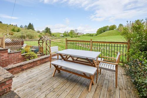 GreenheadHost & Stay - Ramblers Rest Cottage的木甲板上的野餐桌和两把椅子