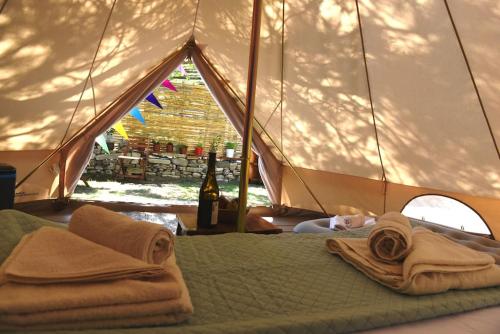 卡拉马基Happy Glamping的帐篷内的一张床位,配有毛巾和一瓶葡萄酒