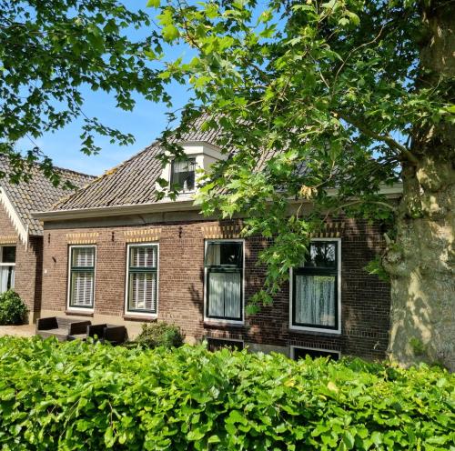 韦斯普Het Voorhuis boerderij Hoeve Vrede Best的一座带窗户和树的老砖屋