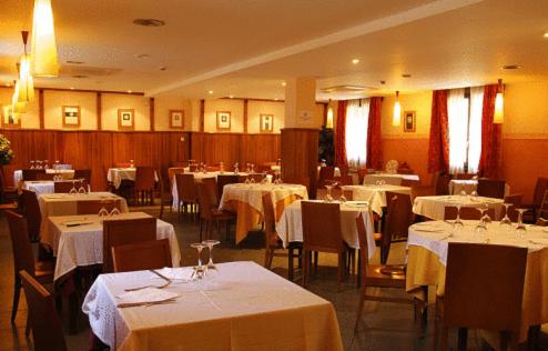 卡斯特洪德索斯比利牛斯山酒店的用餐室配有桌椅和白色桌布