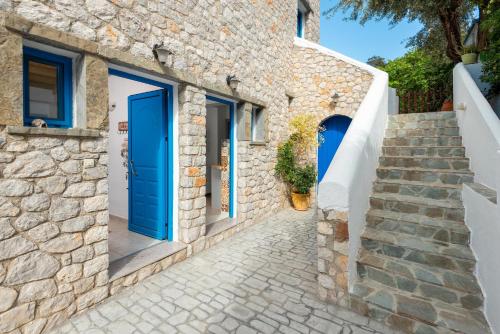 阿彻奇洛斯Agnanti Beach Apartments的石头房子,设有蓝色的门和楼梯