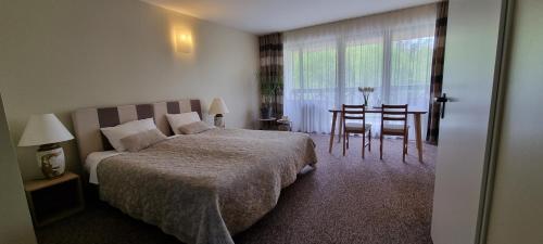 Brivkalni埃尔贝尼旅馆的一间卧室配有一张床铺和一张桌子,还有一间用餐室