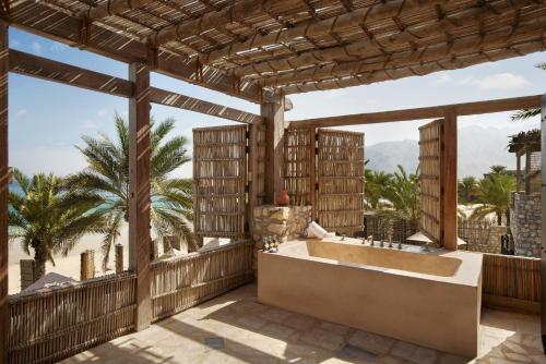 迪巴志加湾六感度假酒店的棕榈树阳台的带浴缸的浴室