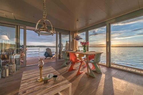 RiethtraumHaff Hausboote La Péniche / Ostsee - außergewöhnliches Design, atemberaubende Sonnenuntergänge und Sauna an Bord的一间配备有桌子的用餐室,享有水景