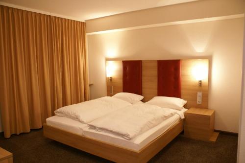 锡根豪斯亨赫酒店的一间卧室配有一张带白色床单的大床