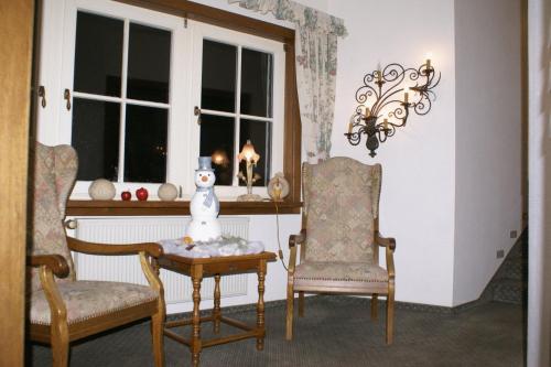 锡根豪斯亨赫酒店的一间房间,配有两把椅子和一张桌子,上面有雪人