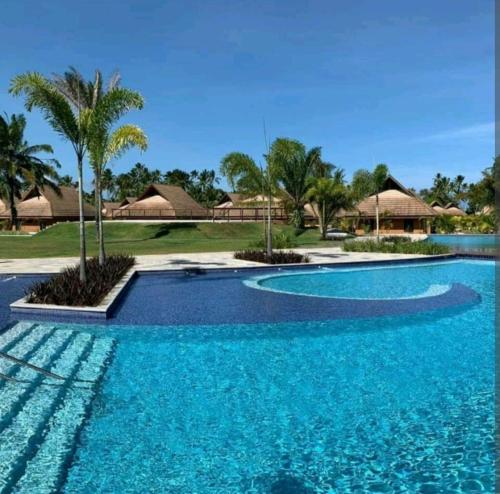 塔曼达雷Eco Resort Praia dos Carneiros - Flats & Bangalô - LocarHouse的一座拥有蓝色海水和棕榈树的游泳池