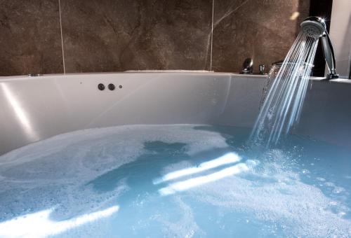 塔兰孔康普利约伊诺图里芬卡艾斯塔酒店的配有蓝色水的浴缸,提供淋浴