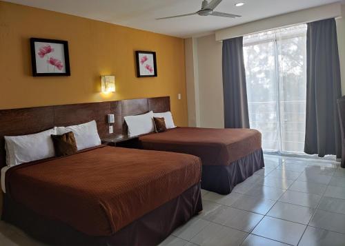 阿瓜斯卡连特斯Posada Del Carmen Aguascalientes的酒店客房设有两张床和窗户。