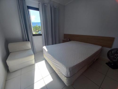 卡拉瓜塔图巴Lindo apartamento com vista para o mar em Caraguá!的卧室配有床、椅子和窗户。