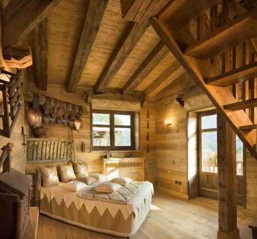 圣贾科莫Chalet Euthalia Restaurant & Suites的卧室配有一张床铺,位于带木墙的房间内