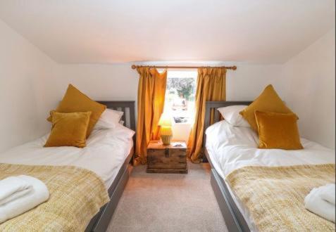 MattishallLavender Cottage的一间卧室设有两张床和窗户。