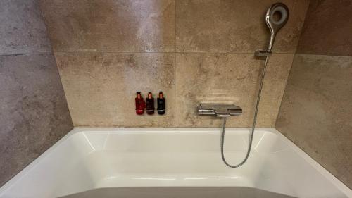 威拉尔-苏-罗伦Zenith Views by Villars Luxury的带淋浴头的浴缸和三瓶