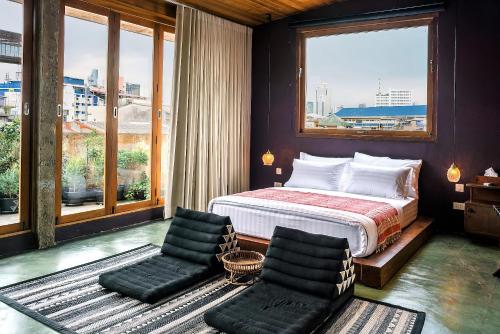曼谷Ba Hao Residence的一间卧室配有一张床、两把椅子和窗户