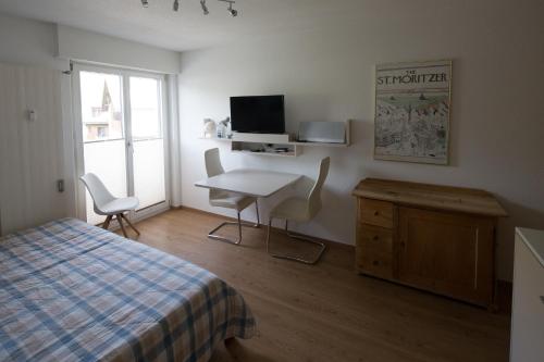 苏尔勒吉Chesa Surlej Apartment的一间卧室配有一张床、一张桌子和一张书桌