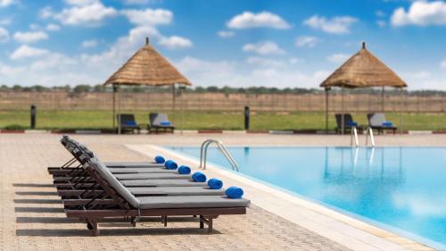 恩贾梅纳Radisson Blu Hotel N'Djamena的度假村的游泳池,配有躺椅和遮阳伞