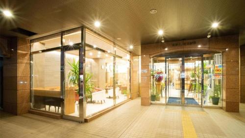 北见Toyoko Inn Hokkaido Kitami Ekimae的装有玻璃门和盆栽的商店前