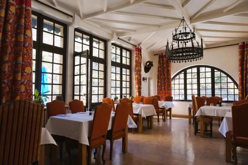 拉马莱恩Hôtel-Restaurant Le Manoir De Montesquiou的一间带桌椅和吊灯的用餐室