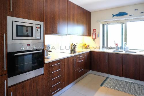 斯代塔维拉Casa Lux Tavira的一间带木制橱柜和微波炉的厨房