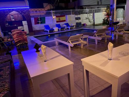 卢克索Luxor Oasis Guest House的带游泳池的客房内的2张桌子和椅子