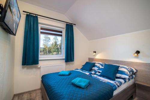 加茨比亚格拉Domki GENAKER的一间卧室配有蓝色的床和蓝色枕头