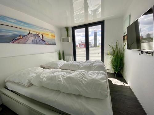 卡珀尔恩Hausboot Ferienhaus Captains Boat的卧室配有一张白色床,墙上挂有绘画作品