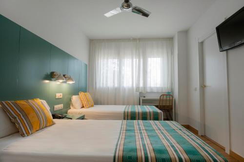 巴塞罗那Yomo Hostal BCN Port的酒店客房设有两张床和电视。