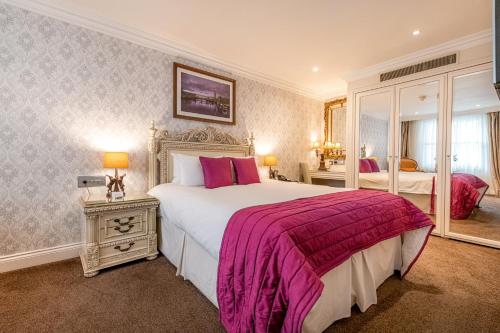 伦敦阿什本酒店的一间卧室配有一张大床和两面镜子
