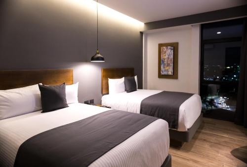 瓜达拉哈拉Gumont Guadalajara López Mateos - Minerva的酒店客房设有两张床和窗户。