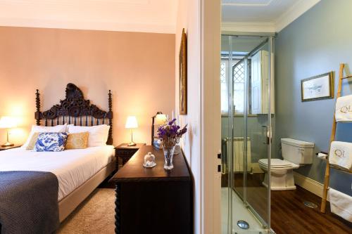 圣孔巴当Quinta Lusitânia的一间卧室设有一张床和一个玻璃淋浴间