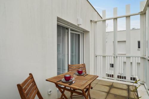 拉罗谢尔Appartement des Tours - Welkeys的阳台配有木桌和椅子,设有窗户