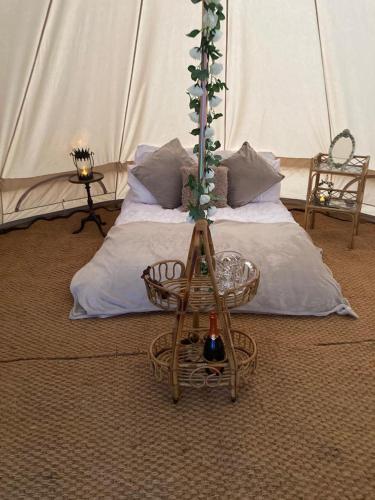 EgmantonSouthfields Bell Tent.的一间设有一张床和一张桌子及一瓶葡萄酒的客房