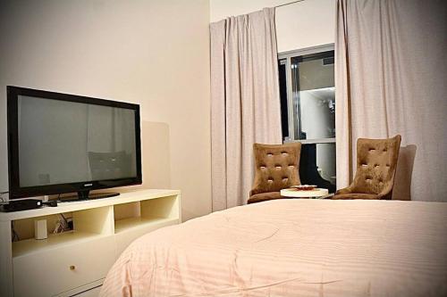 迪拜Cosy Studio in Marina的一间卧室配有一张床、两把椅子和电视
