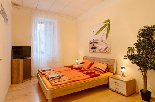 Gaaden加登公寓的一间卧室配有橙色床单和植物