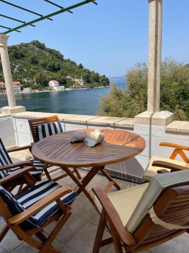 ProžuraBeach house Evita的俯瞰水面的庭院里配有一张木桌和椅子