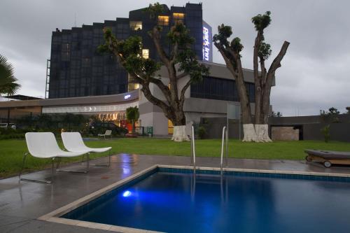 利伯维尔雷迪森利伯维尔公园酒店的一座带两把白色椅子的游泳池和一座建筑