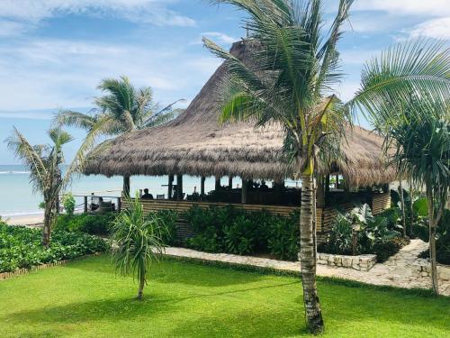 怀卡布巴克Sumba Beach House的拥有茅草屋顶和棕榈树的度假酒店