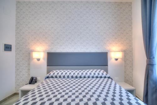 奇维塔韦基亚波尔图迪罗马酒店的一间卧室配有一张带蓝色床头板和灯的床。