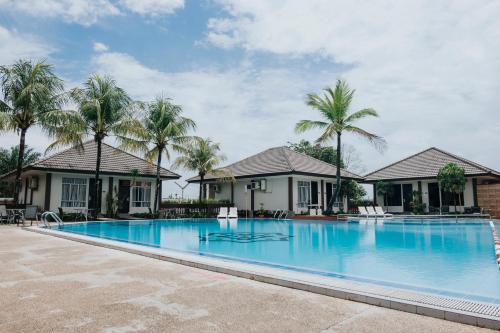 丹戎槟榔丹戎槟榔舒适酒店的棕榈树房屋前的大型游泳池
